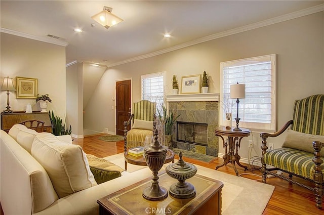 living room featuring a tiled fireplace, wood-type flooring, and crown molding