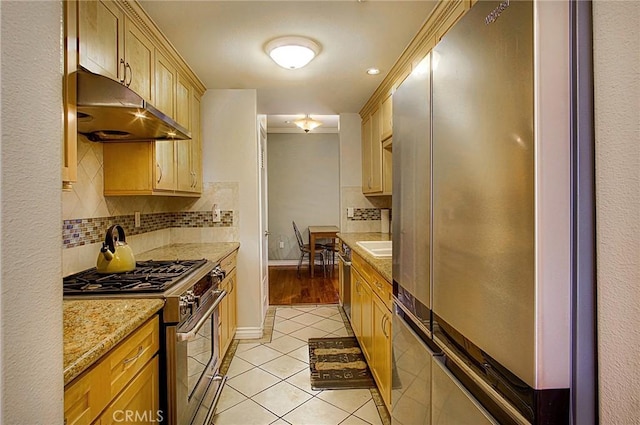 kitchen featuring light brown cabinetry, light tile patterned floors, stainless steel appliances, light stone countertops, and backsplash