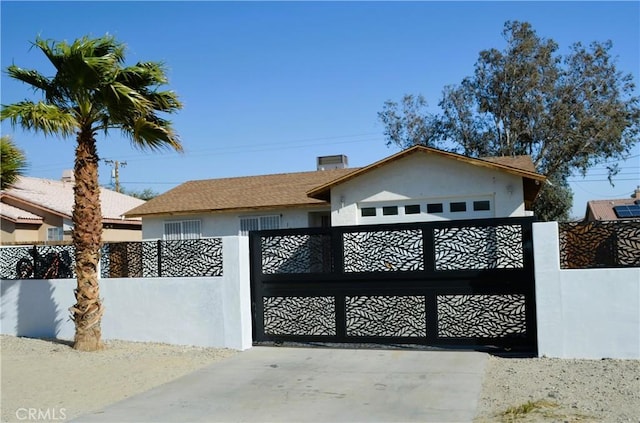 view of front of house featuring a fenced front yard, a gate, concrete driveway, and stucco siding