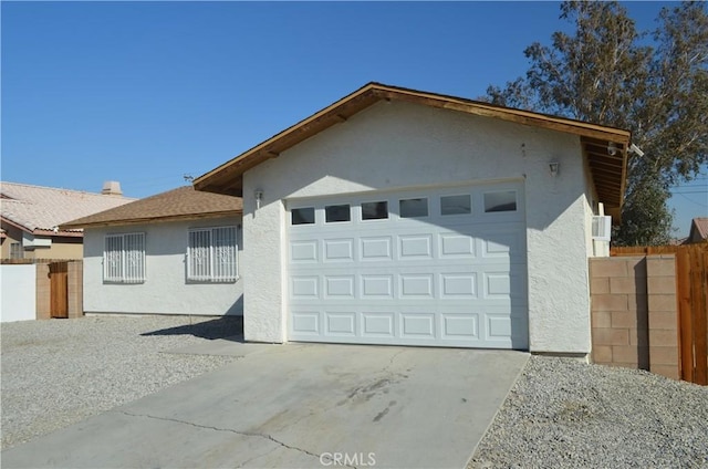 view of front facade with an attached garage, fence, concrete driveway, and stucco siding