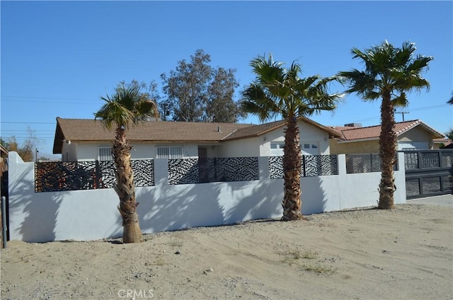 ranch-style house featuring a fenced front yard and stucco siding