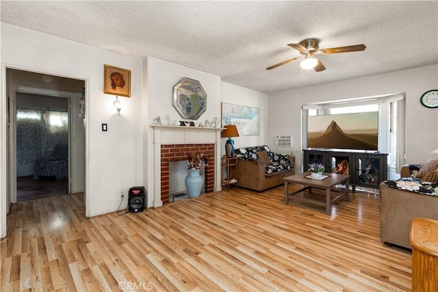 living room with a brick fireplace, light hardwood / wood-style flooring, and a textured ceiling