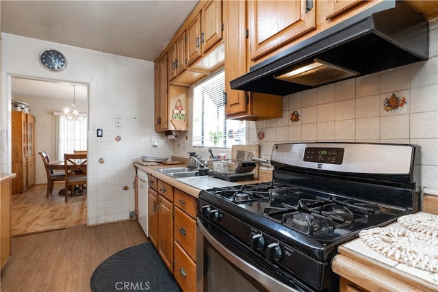 kitchen featuring sink, stainless steel gas range, tile walls, white dishwasher, and light hardwood / wood-style floors