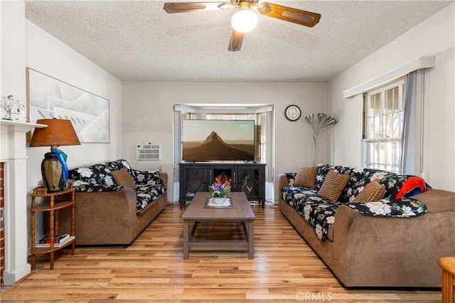 living room with a brick fireplace, a textured ceiling, and light wood-type flooring