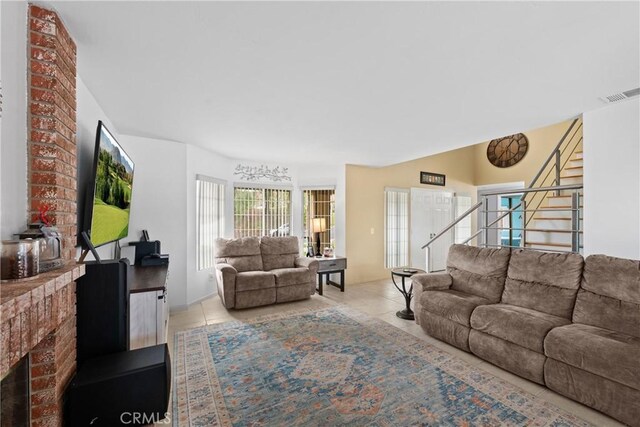 living room featuring a brick fireplace and light tile patterned floors