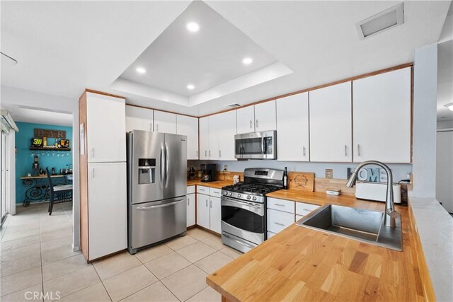 kitchen with white cabinetry, appliances with stainless steel finishes, and a raised ceiling