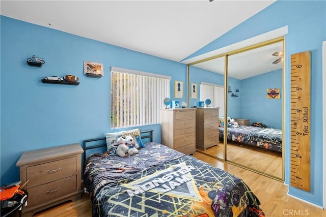 bedroom featuring vaulted ceiling, a closet, and light hardwood / wood-style flooring