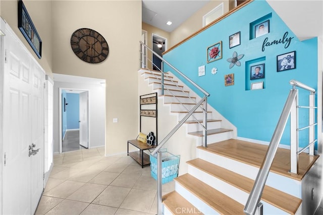 stairs featuring a towering ceiling and tile patterned floors