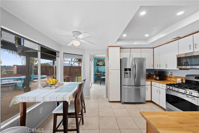 kitchen featuring ceiling fan, appliances with stainless steel finishes, light tile patterned floors, and white cabinets