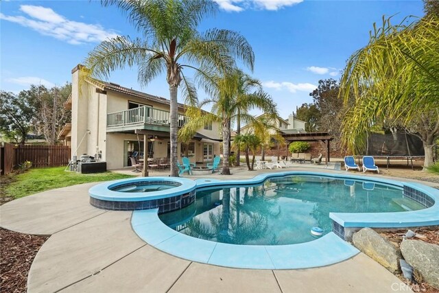 view of swimming pool with a water slide, a trampoline, a pergola, a patio area, and an in ground hot tub