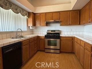 kitchen with dishwasher, sink, tile counters, stainless steel range with gas stovetop, and light hardwood / wood-style flooring