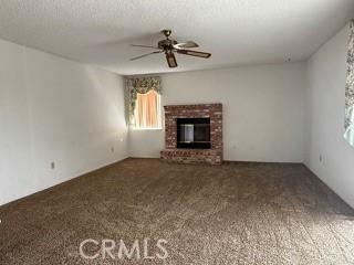 unfurnished living room with ceiling fan, a fireplace, and carpet