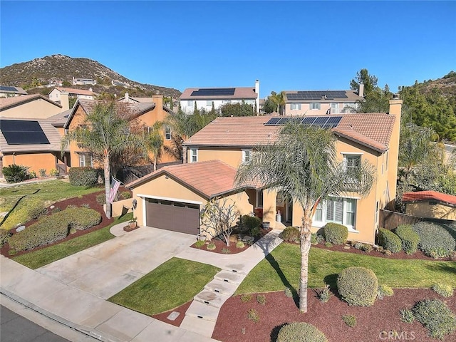 view of front of property featuring a mountain view, a garage, a front yard, and solar panels