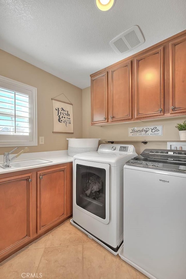 washroom with washing machine and clothes dryer, sink, cabinets, a textured ceiling, and light tile patterned floors