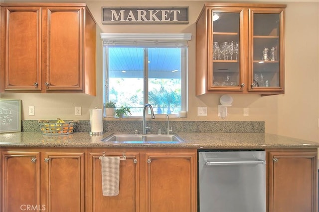 kitchen with light stone counters, stainless steel dishwasher, and sink