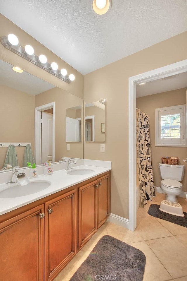 full bathroom featuring toilet, a textured ceiling, vanity, shower / bath combo with shower curtain, and tile patterned flooring