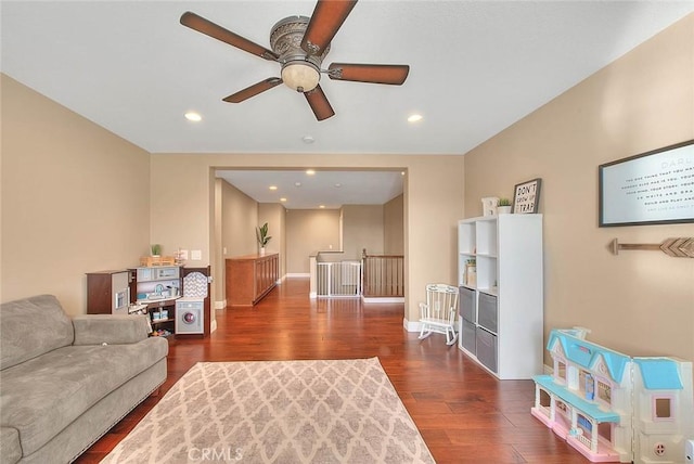 living room featuring ceiling fan and dark hardwood / wood-style flooring