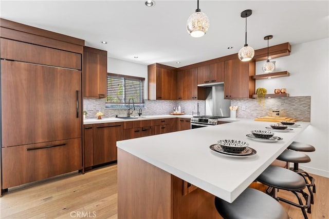 kitchen with sink, pendant lighting, stainless steel range, and a kitchen breakfast bar