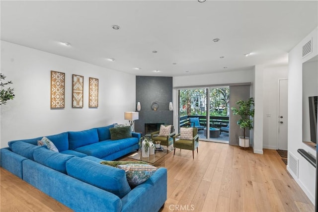 living room featuring a large fireplace and light hardwood / wood-style flooring