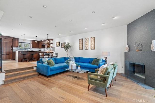 living room with a tiled fireplace and light hardwood / wood-style flooring