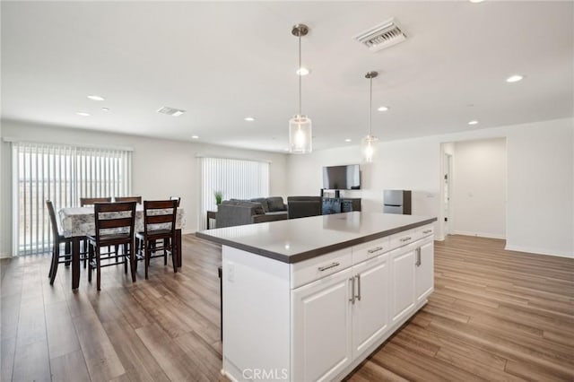 kitchen featuring hanging light fixtures, light hardwood / wood-style flooring, a center island, and white cabinets