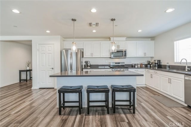 kitchen featuring white cabinetry, stainless steel appliances, sink, and hanging light fixtures