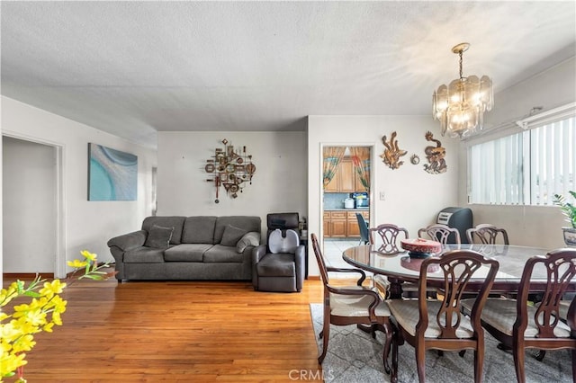 dining space featuring an inviting chandelier, hardwood / wood-style floors, and a textured ceiling