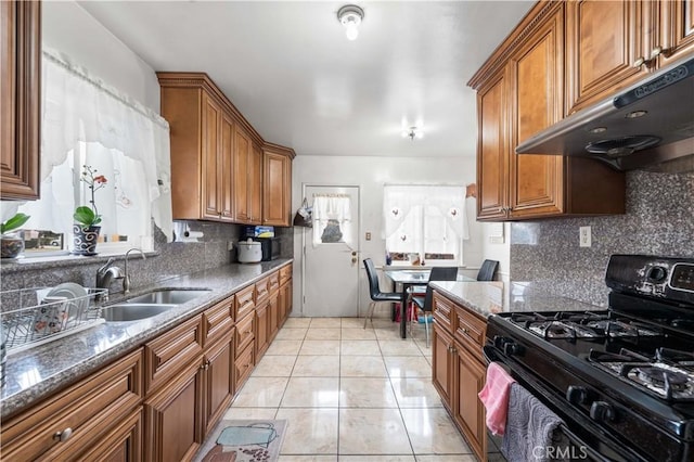 kitchen featuring gas stove, sink, dark stone countertops, and backsplash