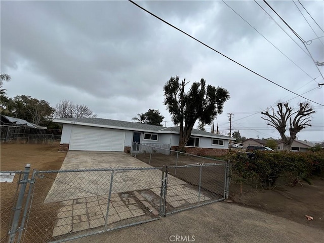 ranch-style home featuring concrete driveway, brick siding, a fenced front yard, and an attached garage