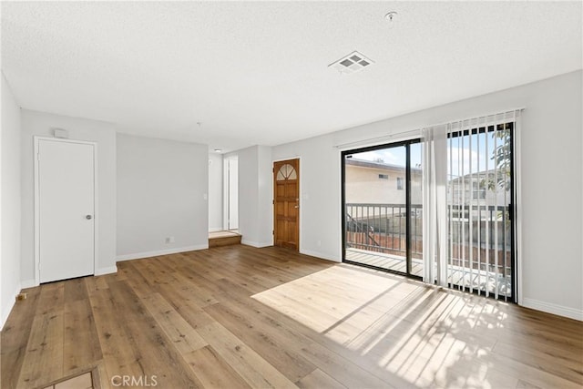 unfurnished room featuring visible vents, light wood-style flooring, baseboards, and a textured ceiling