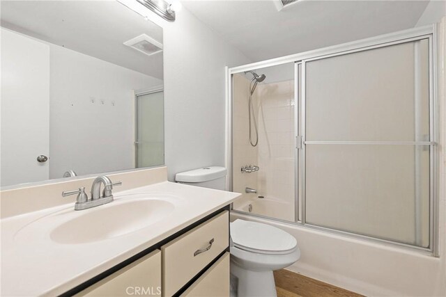 full bathroom featuring enclosed tub / shower combo, vanity, and toilet