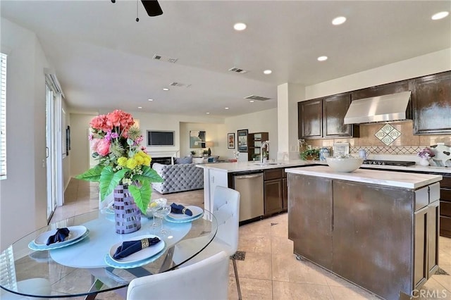 kitchen with appliances with stainless steel finishes, tasteful backsplash, sink, kitchen peninsula, and wall chimney range hood