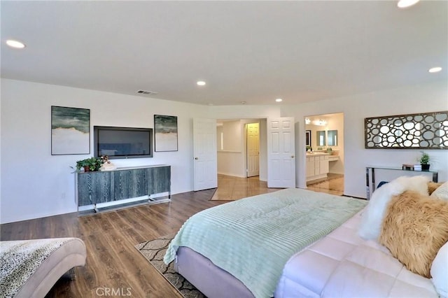 bedroom with ensuite bathroom and hardwood / wood-style floors