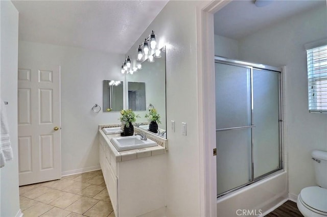 full bathroom featuring vanity, tile patterned flooring, combined bath / shower with glass door, and toilet