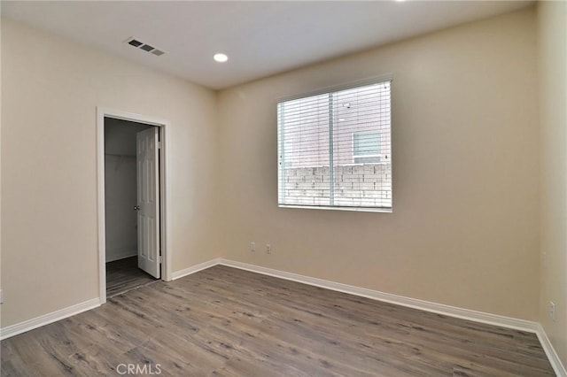 unfurnished bedroom featuring a walk in closet, hardwood / wood-style floors, and a closet