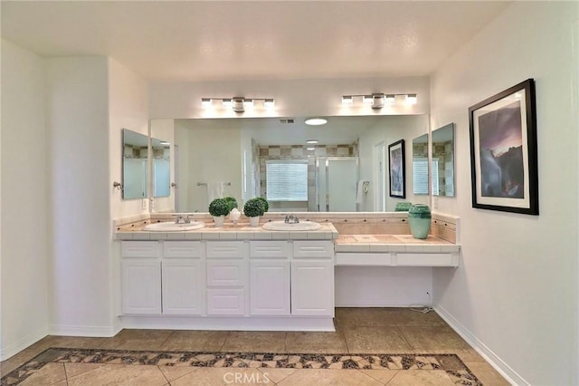 bathroom with a shower with door, vanity, and tile patterned floors