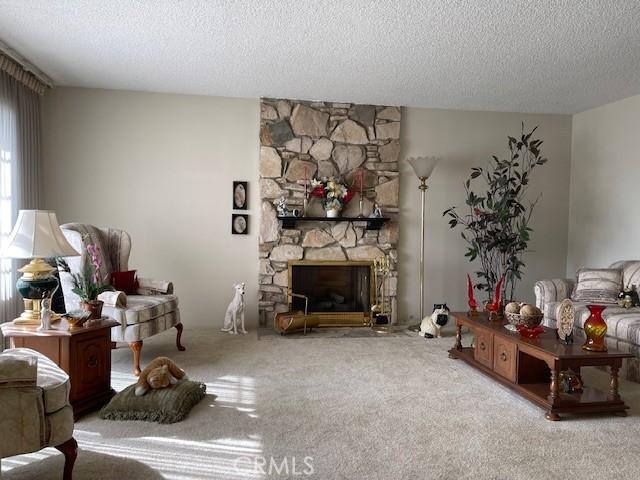 carpeted living room with a fireplace and a textured ceiling