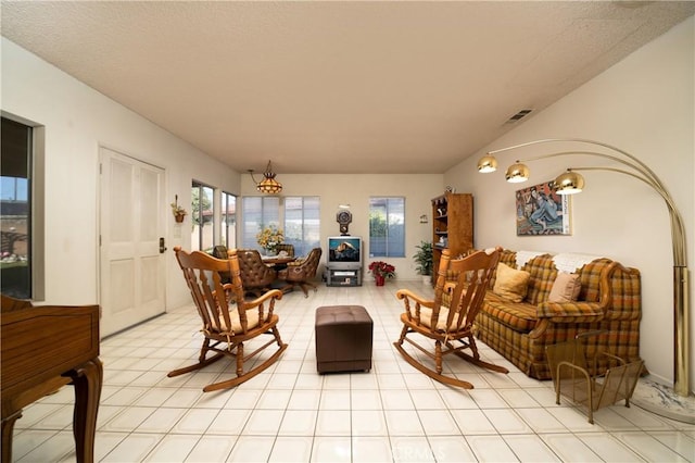 living room with visible vents, vaulted ceiling, and light tile patterned flooring