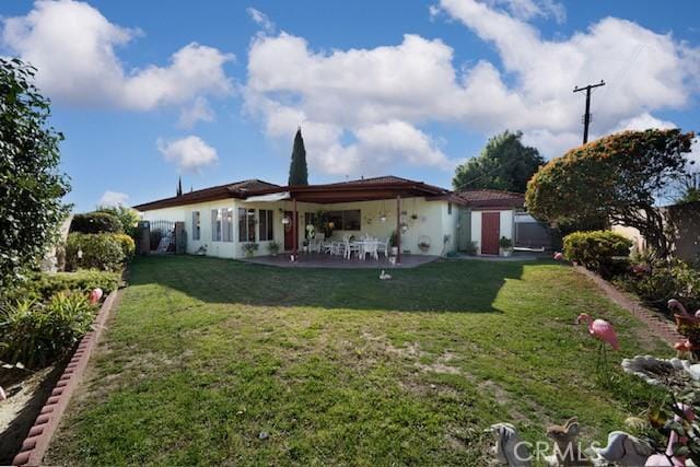 back of house with a patio and a lawn