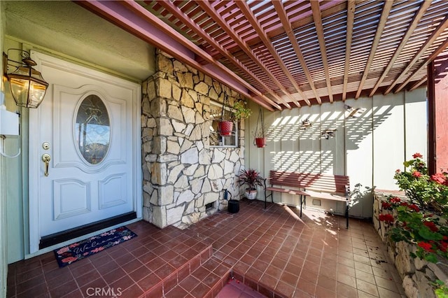 property entrance featuring stone siding, crawl space, and a pergola