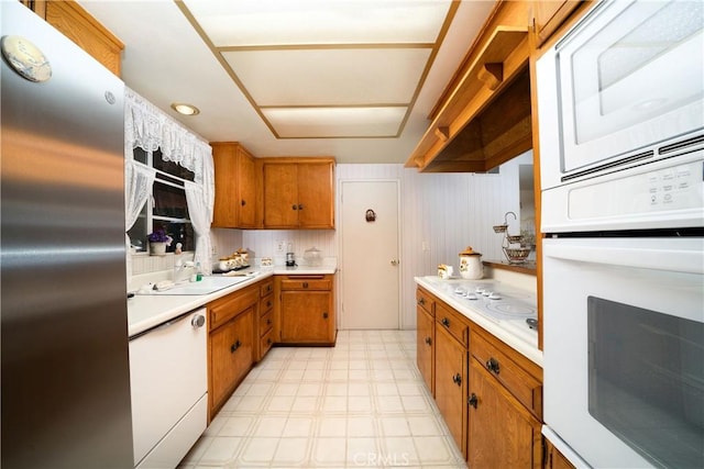 kitchen featuring white appliances, brown cabinetry, light floors, and light countertops