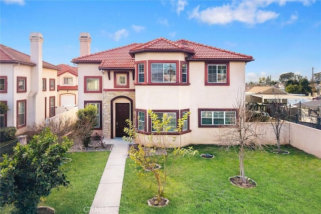 mediterranean / spanish-style home featuring fence, stone siding, stucco siding, a front lawn, and a chimney