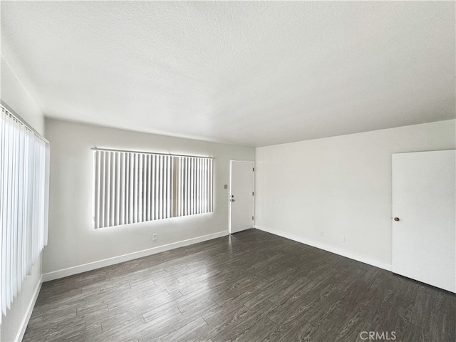 spare room featuring dark wood-type flooring and a textured ceiling