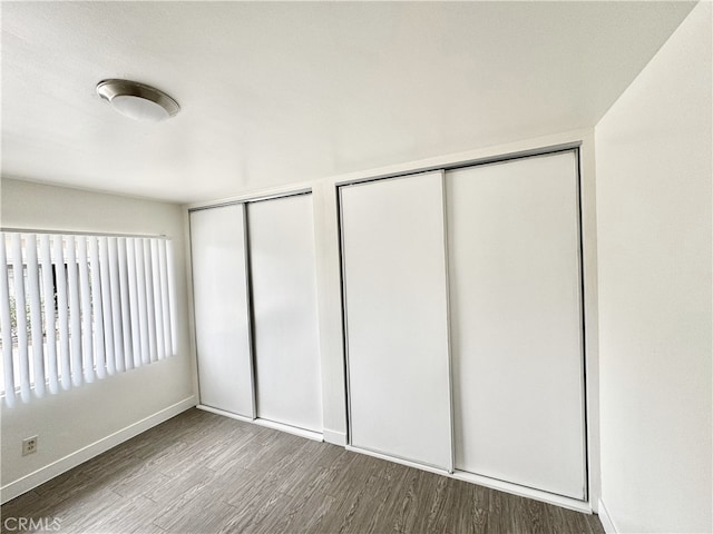 unfurnished bedroom with hardwood / wood-style flooring and two closets