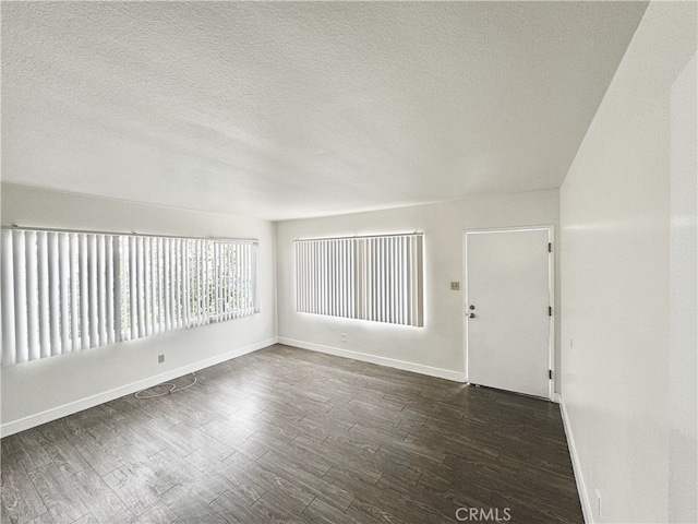 spare room featuring dark hardwood / wood-style floors and a textured ceiling