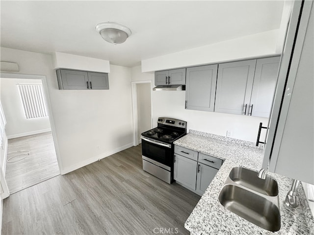 kitchen with gray cabinets, stainless steel electric range oven, sink, and light hardwood / wood-style floors