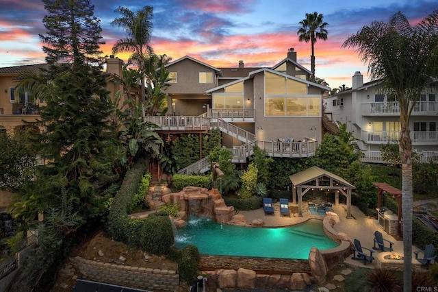 back house at dusk with a gazebo, pool water feature, and a patio