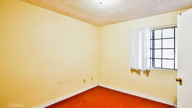 empty room with hardwood / wood-style flooring and a textured ceiling