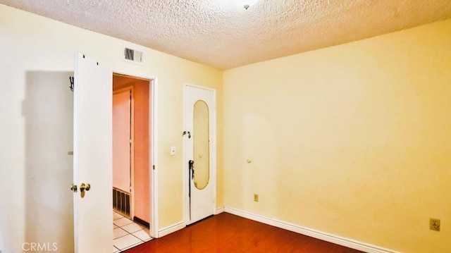 empty room with a textured ceiling and light wood-type flooring