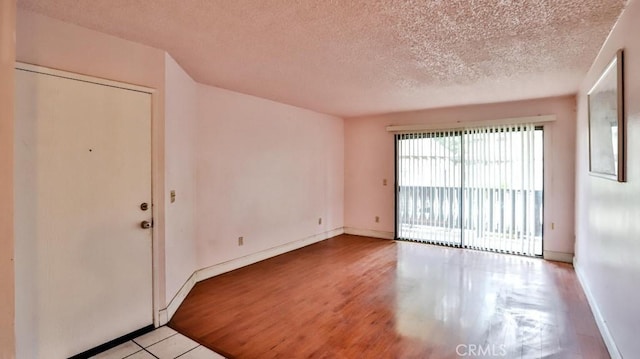 unfurnished room with a textured ceiling and light hardwood / wood-style floors